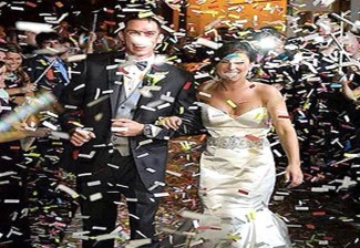 A person and person walking down the aisle with confetti falling  Description automatically generated